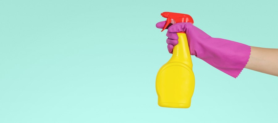 gloved hand holding cleaning spray bottle